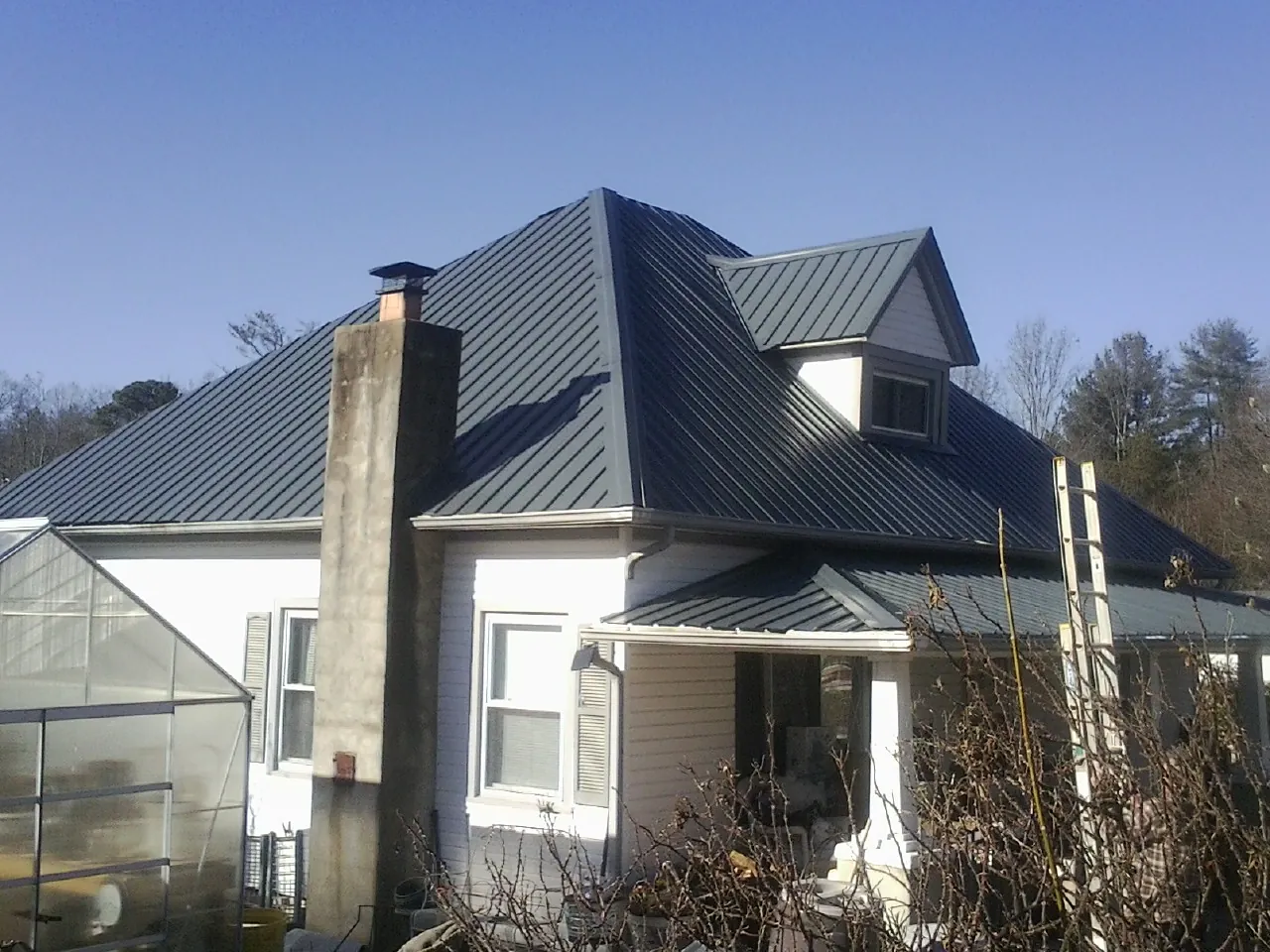Dark blue standing seam metal roof on a white farmhouse with dormer — Slate & Tile Roof Repair by Roofing Brothers in Chocorua