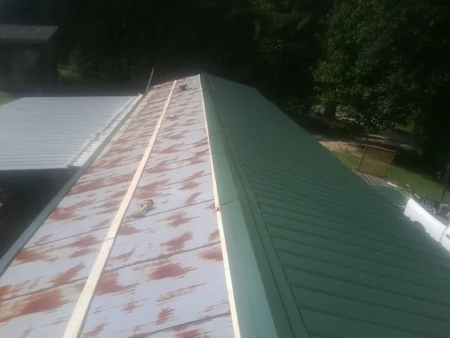 Old rusted panels beside newly installed green metal roofing — Wind Damage Roof Repair by Roofing Brothers in Chocorua