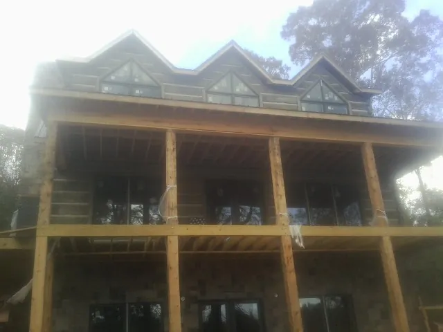 Dormers and porch framing on a large log home under construction — Roof Coating work by our crew in Chocorua