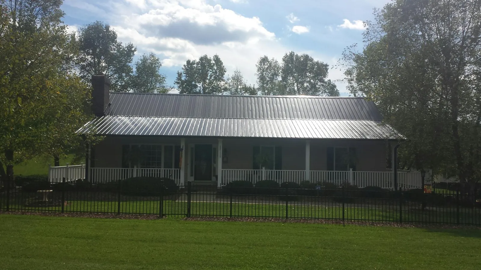 Gray metal roof on a brick ranch with a full width front porch — Gutter Guard Installation work by our crew in Chocorua