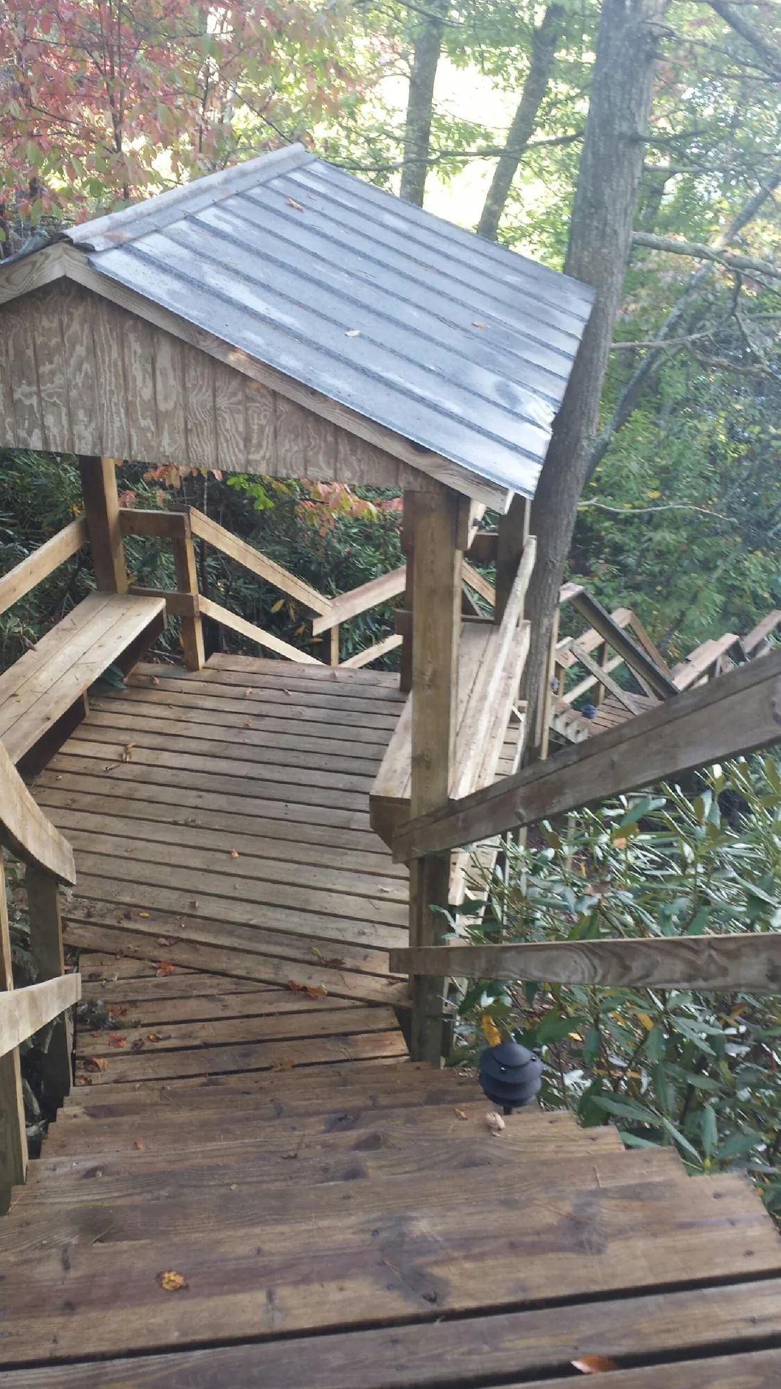 Metal roofed shelter over wooden steps on a wooded walkway — Skylight Repair & Installation work by our crew in Chocorua