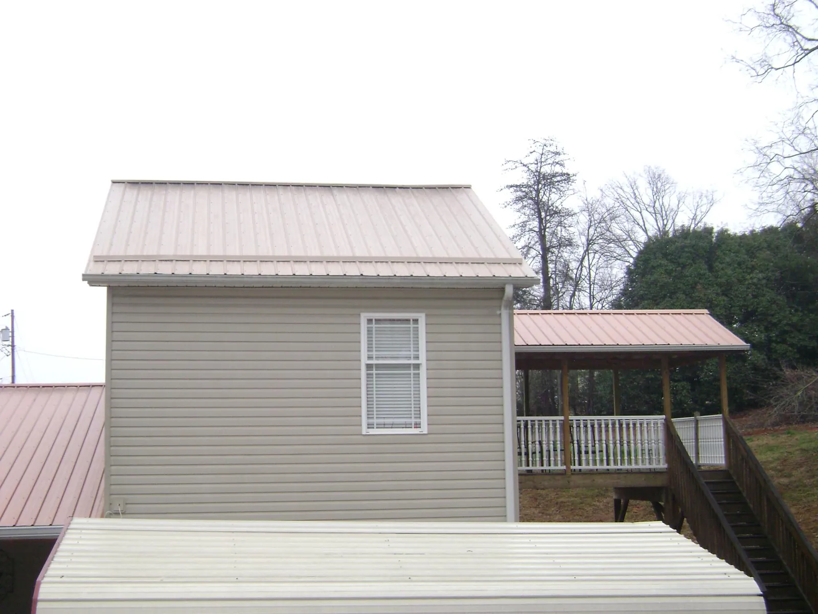 Tan metal roofs on a two story addition and attached porch, from a Roof Replacement job in Chocorua