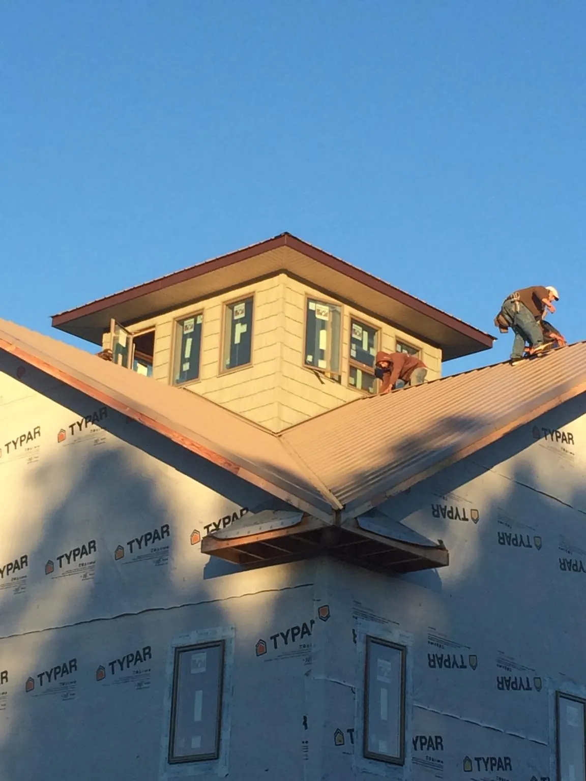 Roofers working around a rooftop cupola on a new metal roof at sunset — Roof Waterproofing in Chocorua by Roofing Brothers